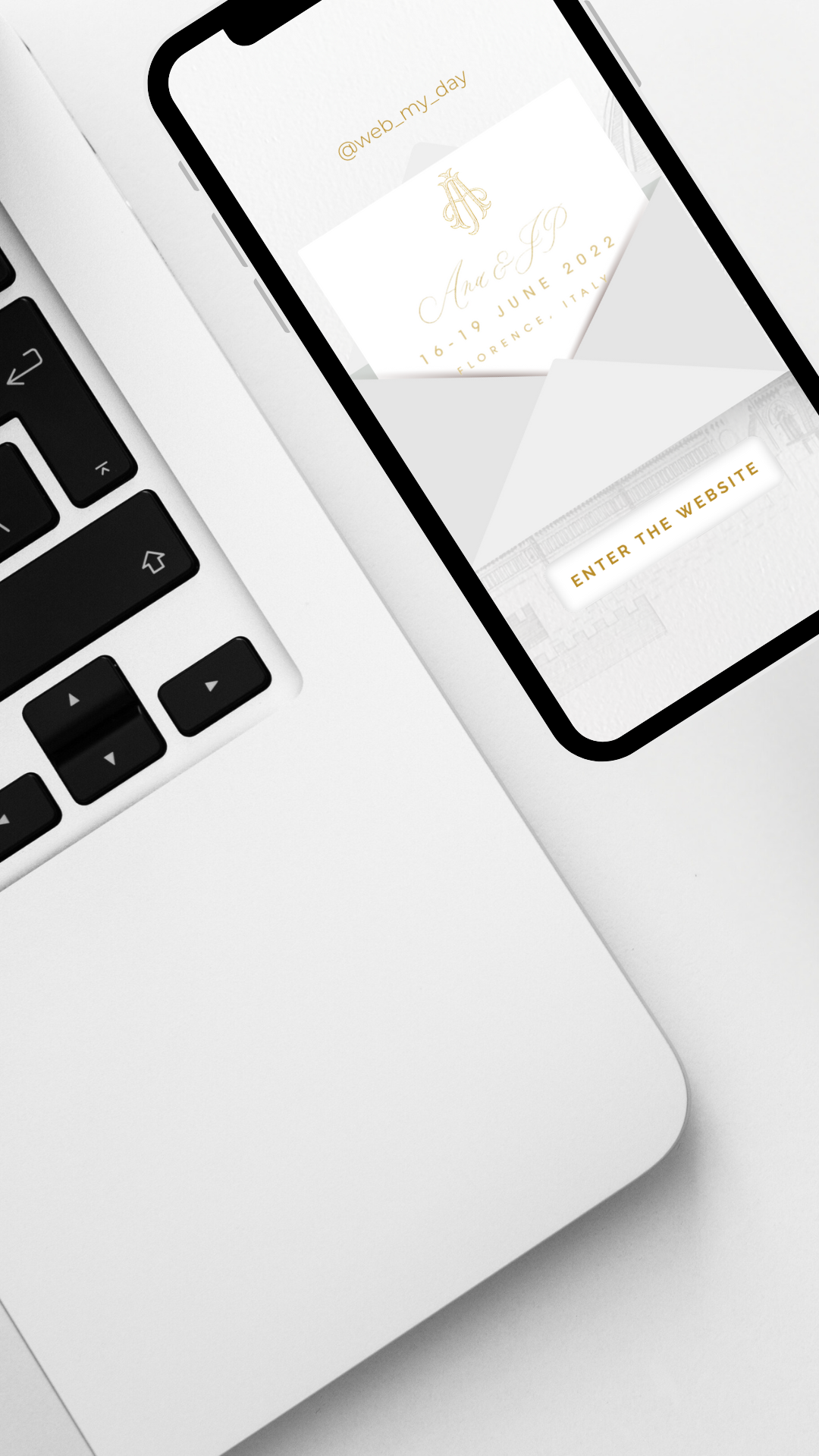 A smartphone displaying a digital wedding invitation rests on a white Apple laptop keyboard. The invitation features elegant gold text and includes details of the wedding date and location, along with a prompt to "Enter the Website.