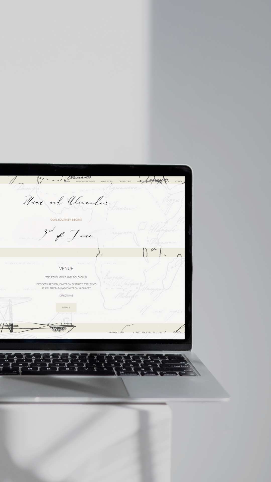 A laptop on a white table displays a webpage with elegant, handwritten script and sections titled "Our Journey Begins" and "Venue." The background features a light, abstract map design. The setting is minimalistic with natural light casting shadows.